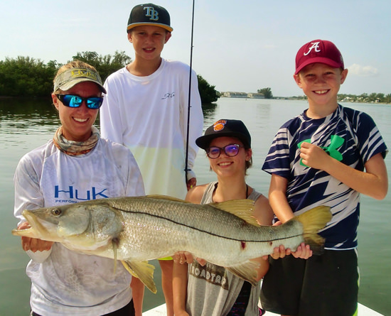 A group of kids holding a large snook caught with Capt. Kelly around Pine Island Sound.